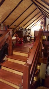 An Attic Room With Wooden Stairs and Table With Chair